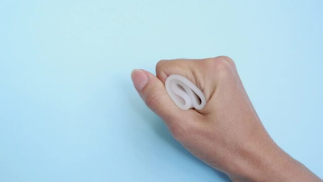 Close-up of a woman's hand holding a menstrual cup against a blue background. Women's health concept, zero waste alternatives
