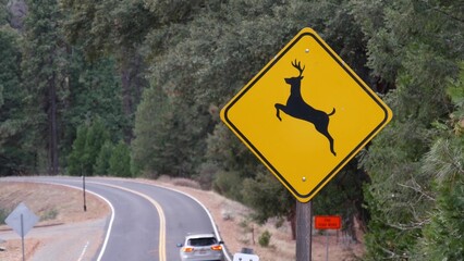 Deer crossing warning yellow sign, California USA. Wild animals xing traffic signage for safety...
