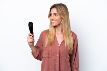 Singer Uruguayan woman picking up a microphone isolated on white background looking side