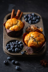 Sweet homemade pastries muffin with blueberries and fresh berries on dark background.