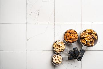 Assortment of nuts in bowls on white background top view with copy space. Healthy snack food.