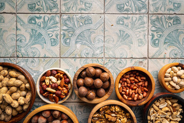 Assortment of nuts in a bowls on blue tile background top view with copy space. Healthy snack food.