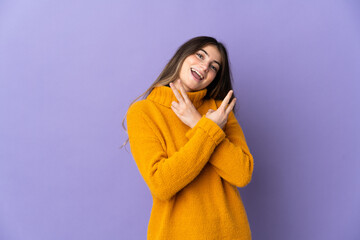 Young caucasian woman isolated on purple background smiling and showing victory sign