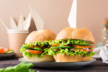 Veggie burger with fresh vegetables and lettuce in a bun with sesame seeds on a plate. Close-up