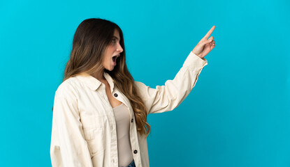 Young caucasian woman isolated on blue background pointing away