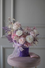Beautiful composition with peonies and roses in a purpl box on pink chair. Bouquet of tenders peonies a girl for mother's day, valentine's day, Woman's day 8 march.