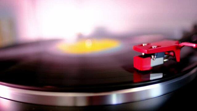 close-up of black vinyl record, disk is spinning, colored lights, analogue retro music concept, audio experience, relaxation, musical enjoyment, vintage technology, nostalgia for the past