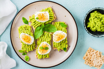 Bruschetta on crispy bread with avocado and boiled egg on a plate. Top view. Close-up