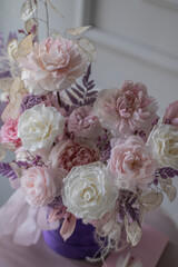 Beautiful composition with peonies and roses in a purpl box on pink chair. Bouquet of tenders peonies a girl for mother's day, valentine's day, Woman's day 8 march.
