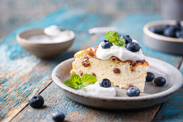 Baked homemade cottage cheese casserole or pudding with raisins serving with blueberry and sour...