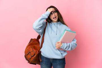 Young student woman isolated on pink background doing surprise gesture while looking to the side