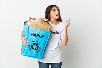 Young woman holding a recycling bag full of paper to recycle isolated on white background thinking an idea pointing the finger up