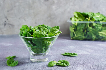 Fresh baby spinach leaves in a glass bowl and behind on a texture table. Detox vitamin diet