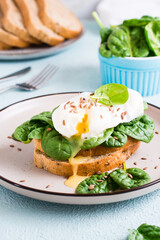 Appetizing sandwich with poached egg, spinach and flax seeds on a plate. Flexetarian Diet. Vertical