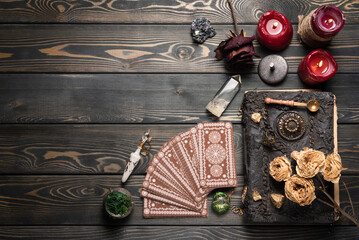 Tarot cards and book of magic on the wooden table background with copy space.