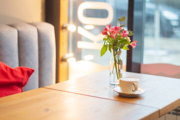 cappuccino coffee and flowers on the table in the cafe. a table in a cafe