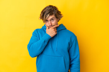 Handsome blonde man isolated on yellow background having doubts