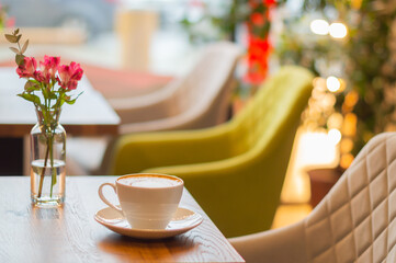 cappuccino coffee and flowers on the table in the cafe. a table in a cafe