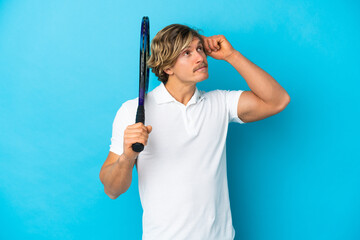 blonde tennis player man isolated on blue background having doubts and thinking