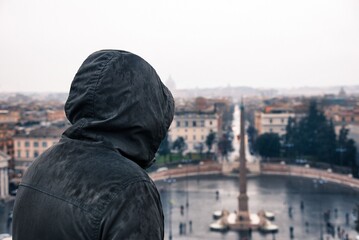 Hombre encapuchado viendo roma bajo la lluvia