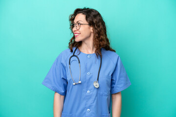 Young nurse caucasian woman isolated on blue background looking side