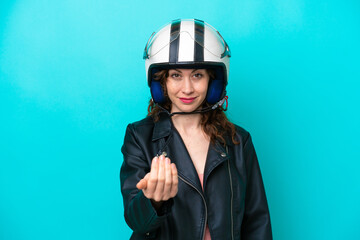 Young caucasian woman with a motorcycle helmet isolated on blue background inviting to come with hand. Happy that you came