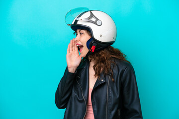 Young caucasian woman with a motorcycle helmet isolated on blue background shouting with mouth wide open to the side