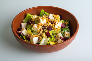 Spring salad with chicken fillet, feta cubes, breadcrumbs, quail eggs, on a clay plate isolated on a white background. Selective focus. The concept of delicious spring salads