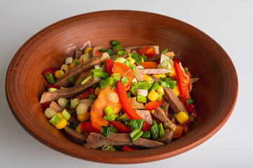 Spring vegetable salad, tongue, pepper, tomato, corn, breadcrumbs, quail eggs, on a clay plate isolated on a white background. Selective focus. The concept of delicious spring salads