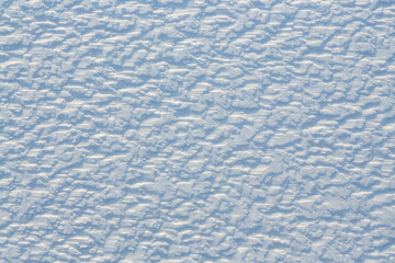 Beautiful winter background with snowy ground. Natural snow texture. Wind sculpted patterns on snow surface.