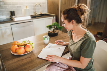 Woman Making To Do List While Enjoying Morning Coffee At Home