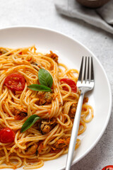 Cooked pasta with mussels, cherry tomatoes, basil in white plate with fork. Close up. Mediterranean food