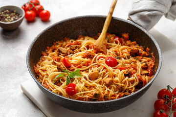 Pasta Spaghetti with Seafood, mussels pasta with tomatoes sauce in frying cooking pan with cherry tomatoes and basil.