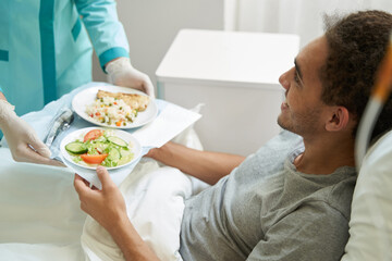 Happy man getting meal on tray from medical center worker