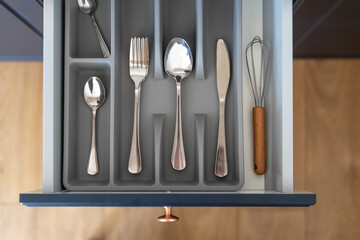 Opened kitchen drawer with clean cutlery set