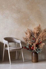 Comfortable armchair and flowers in vase against wall