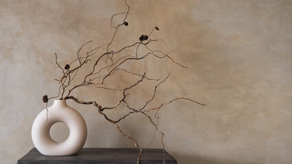 Dry branch of in round modern white vase against beige wall