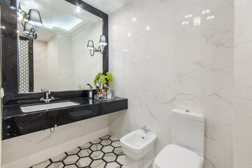 Luxury bathroom design made of black and white marble with original floor tiles. A huge mirror...