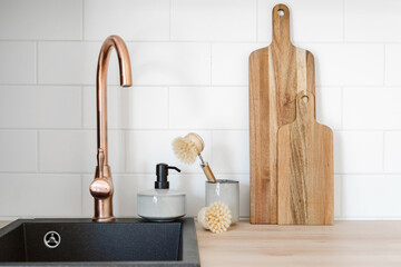 Household objects standing near black modern sink with copper faucet