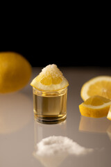 shot glass with salt and lemon on a glass table against a black background