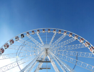 The top part of the giant ferris wheel in Krakow against a bright blue sky in the midday light....