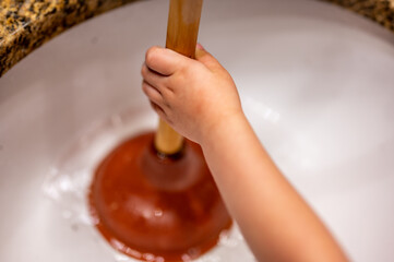 Using a plunger on a bathroom sink plugged with Hair and scum in a pool of stagnant standing water.