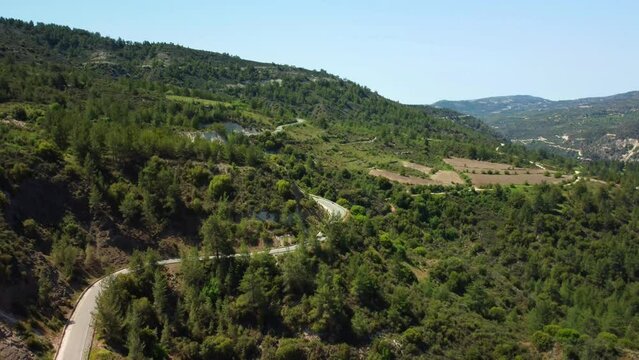 Road in the green forests of the mountain Troodos in Cyprus in the spring on a sunny day. Aerial view.