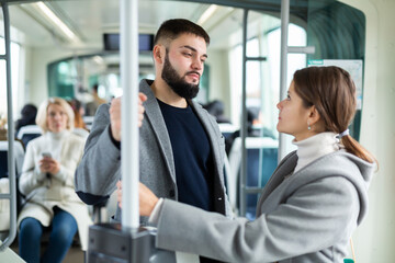 Attractive girl and bearded guy talking in city bus on way to work in fall day..