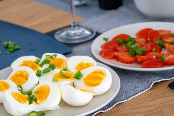 homemade breakfast, yellow cheese with holes, small sliced tomatoes, cottage cheese, egg paste, eggs, chives, tea, orange, carrot and grapefruit juice in wine glasses, black tableware.