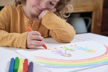 Thoughtful child drawing LGBT family with crayons