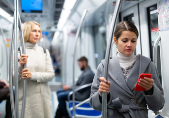 Positive woman reading from mobile phone screen in metro