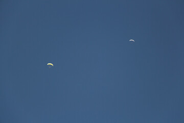 Two paragliders in the blue sky in a sunny day.