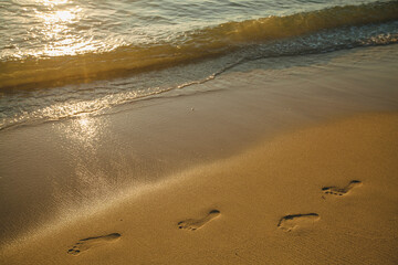 Footprints of bare feet left on the sand on the beach of the sea.