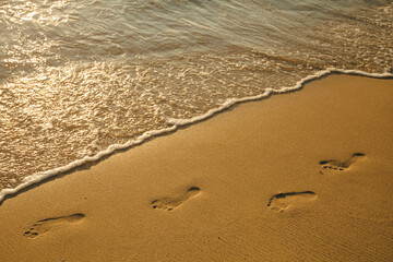 Footprints of bare feet on the beach sand.